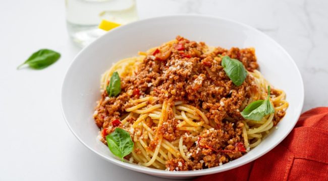 macarrão espaguete ao molho bolonhesa com folhas de manjericão