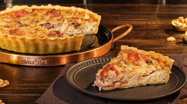 quiche de queijo e presunto com uma fatia servida em louça escura
