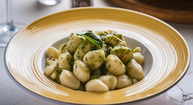 nhoque servido com molho pesto de pistache em prato fundo e decorado.